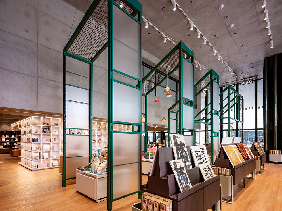 The inside of a boutique shop. Four tall steel-and-glass structures form arches under which tables of merchandise sit.