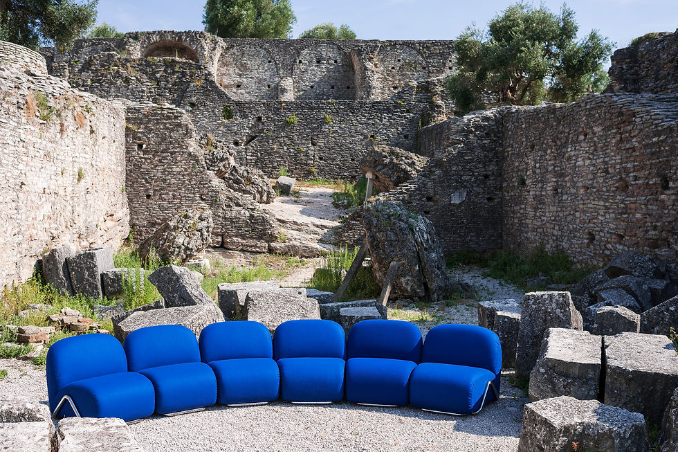 A bright blue modular curved sofa from Tacchini sits in front of the ruins of an ancient building.
