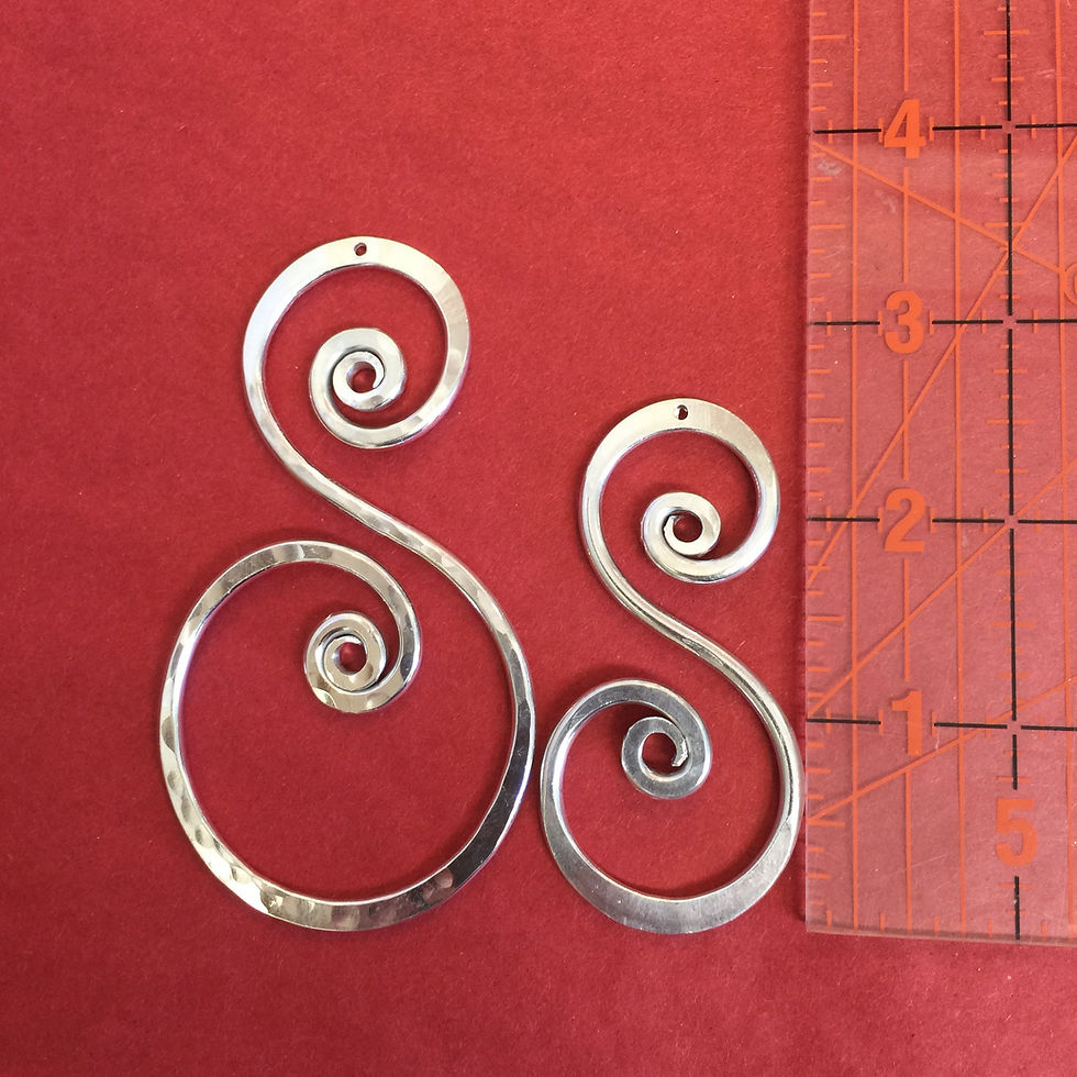 Thumbnail: Two silver spiral pendants on red background with ruler.