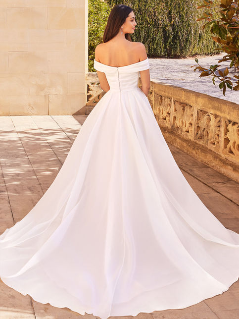 Abito da sposa linea A in organza con corpetto plissettato, spalline off-shoulder, gonna con tasche e spacco, bottoni rivestiti sul retro e strascico chapel elegante