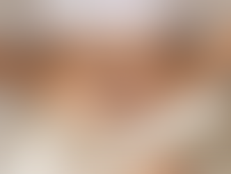 Frau liegt auf dem Bett und hält sich mit beiden Händen den Unterbauch – Symbolbild für Menstruationsbeschwerden oder Bauchschmerzen.