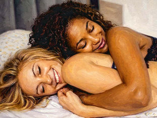 Zwei Frauen liegen lächelnd und eng umschlungen im Bett; ihre Körperhaltung strahlt Nähe, Geborgenheit und entspannte Intimität aus.