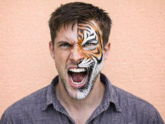 Man with half-painted tiger face screaming, symbolizing the power of the inner animal and primal instincts
