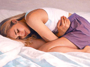 Frau liegt zusammengerollt im Bett und hält ihren Unterbauch – Symbolbild für Endometriose-Schmerzen und zyklusbedingte Unterbauchbeschwerden.