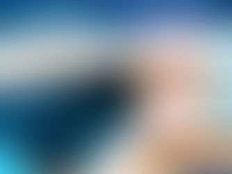 Close-up of a person lying on a treatment table, receiving a gentle abdominal massage or treatment with both hands from another person.