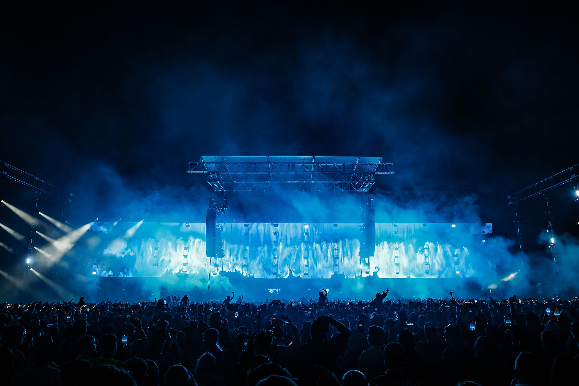 Festival stage at night with atmospheric blue lighting and smoke