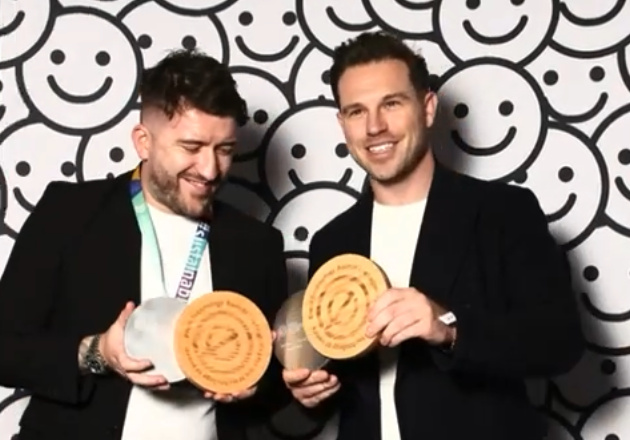 Two men with awards smile for camera