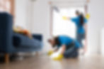 two professional cleaners do clean the floor under the sofa and window