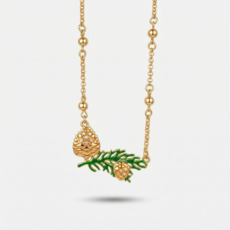 Collana BySimon dorata con due pigne, ramo verde e sfere lungo la catena.