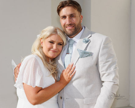 Smiling newlywed couple embracing, light background. Experienced photographer's work.