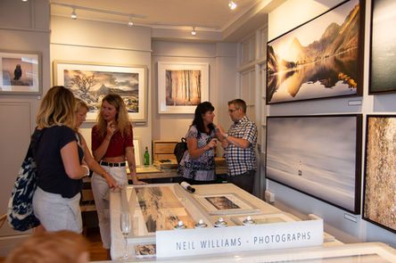 People viewing Neil Williams Photographs at a bright art gallery exhibition.