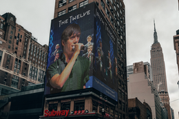 Digital billboard featuring Seph Stanek and the Twelve Irish Tenors on their international concert tour, framed by sky scrape