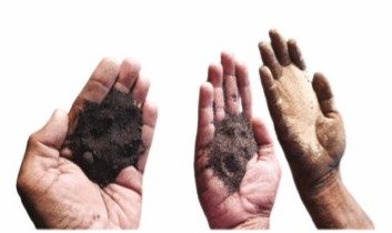 Hands holding used black sand and reclaimed light sand