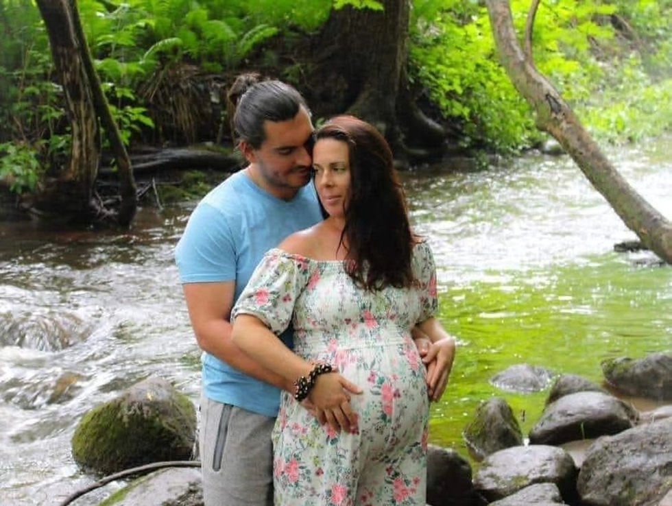 une mère qui porte un enfant dans son ventre et son mari qui la couvre