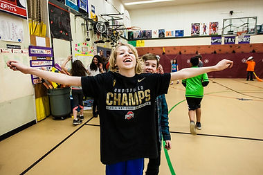 Child with arms spread, wearing a shirt that reads "Champs"