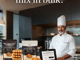 A professional chef in a white uniform and tall hat stands in a modern commercial kitchen next to a white countertop. On the counter are two large premium bulk bags of GoldenWaffle waffle mix, stacks of golden Belgian waffles, and an open laptop displaying the website www.GoldenWaffle.com. Large elegant white text at the top reads “Can I buy waffle mix in bulk?” and the website address www.GoldenWaffle.com appears at the bottom.