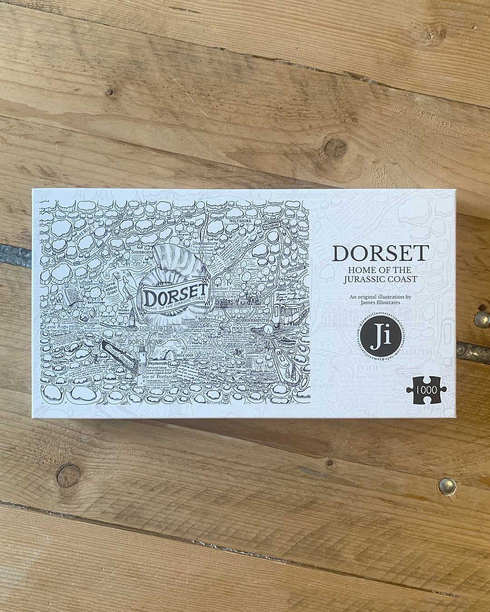 Dorset jigsaw puzzle by James Illustrates box on a wooden dining table.