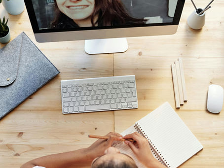 Jeune femme qui apprend le français avec des ocurs de français en ligne. Elle est assise devant un ordinateur et apprend le français avec un cours de français en ligne