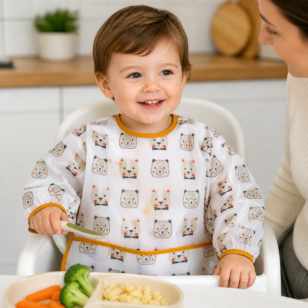 Toddler wearing the white bear-print long-sleeved smock during a supervised meal