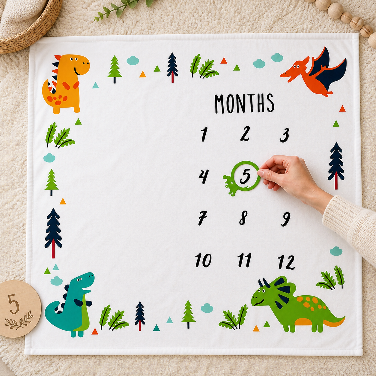 Overhead detail of a dinosaur milestone blanket with a green marker around month five.
