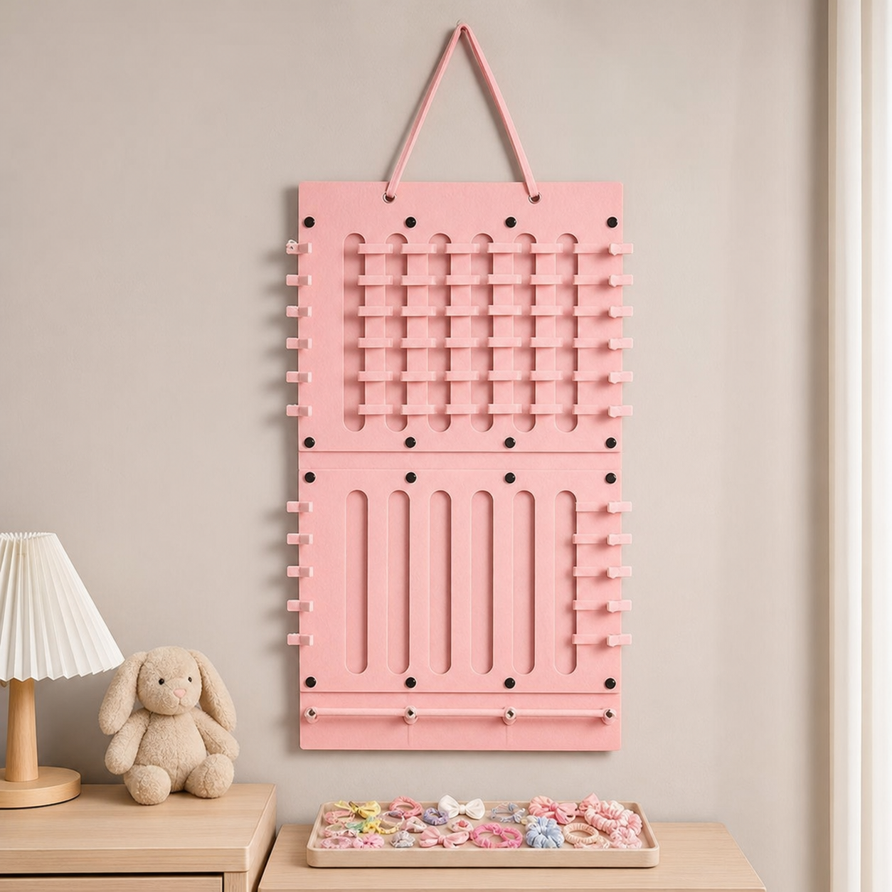 Empty pink vertical two-panel hair-accessory organizer hanging above a tray of loose accessories