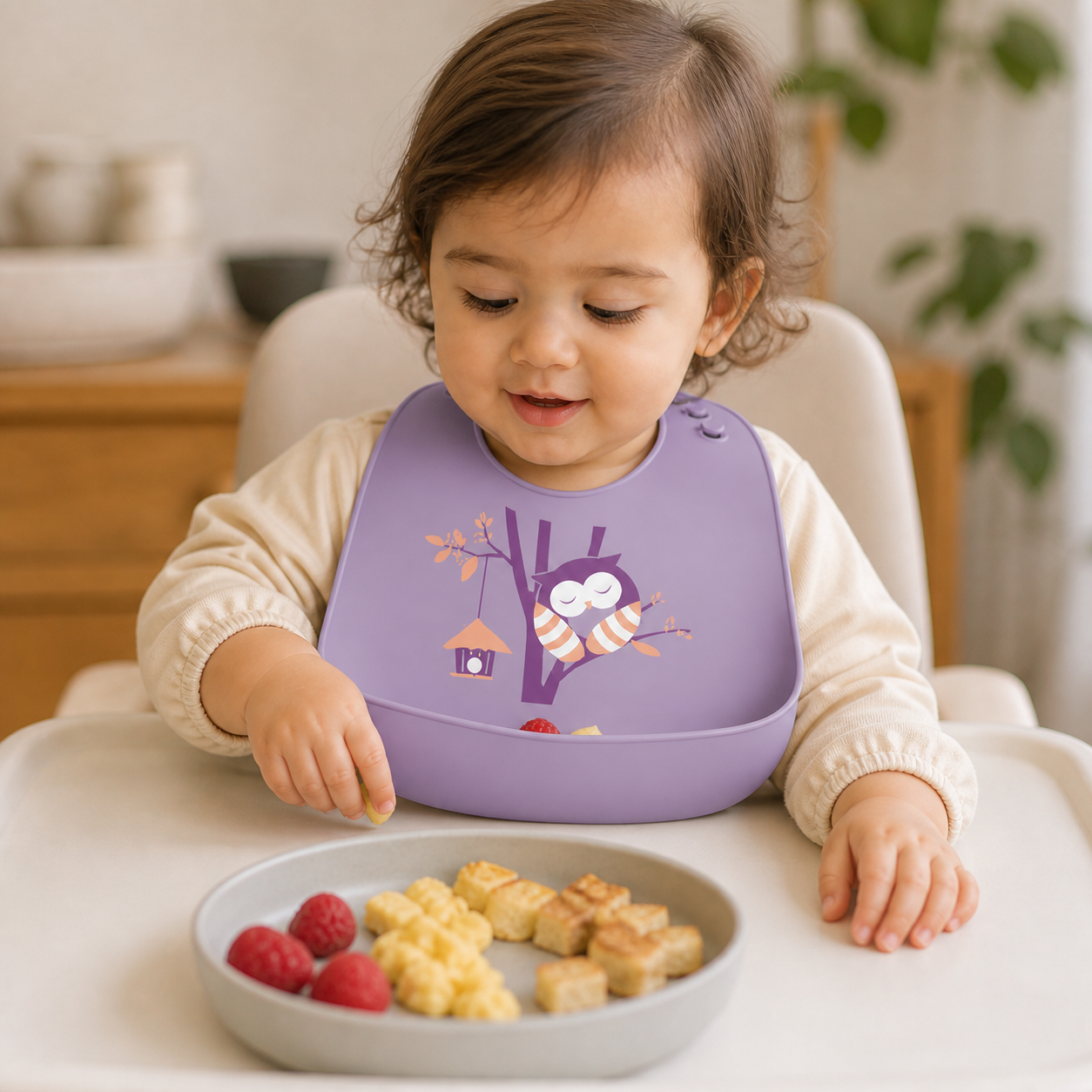 Toddler wearing the Purple Owl silicone bib while food collects in its front pocket