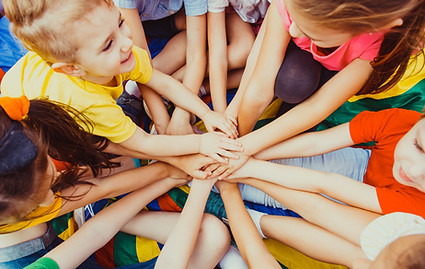 Glückliche Kinder im Kita-Patenprogramm halten ihre Hände aufeinander.