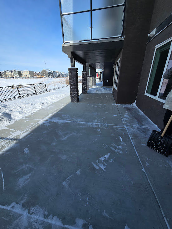 Snow removal crew clearing a residential pad and sidewalk in Calgary, Alberta after a winter snowfall, ensuring safe access for homeowners and pedestrians.