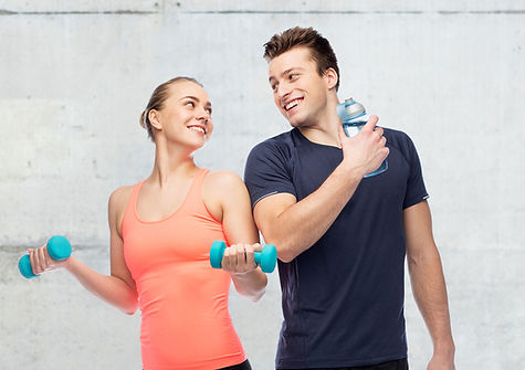 sport-fitness-people-concept-happy-sportive-man-woman-with-dumbbell-water-bottle-concrete-