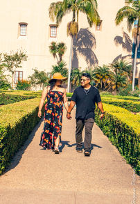 Couple holding hands walking a garden path with palm trees.