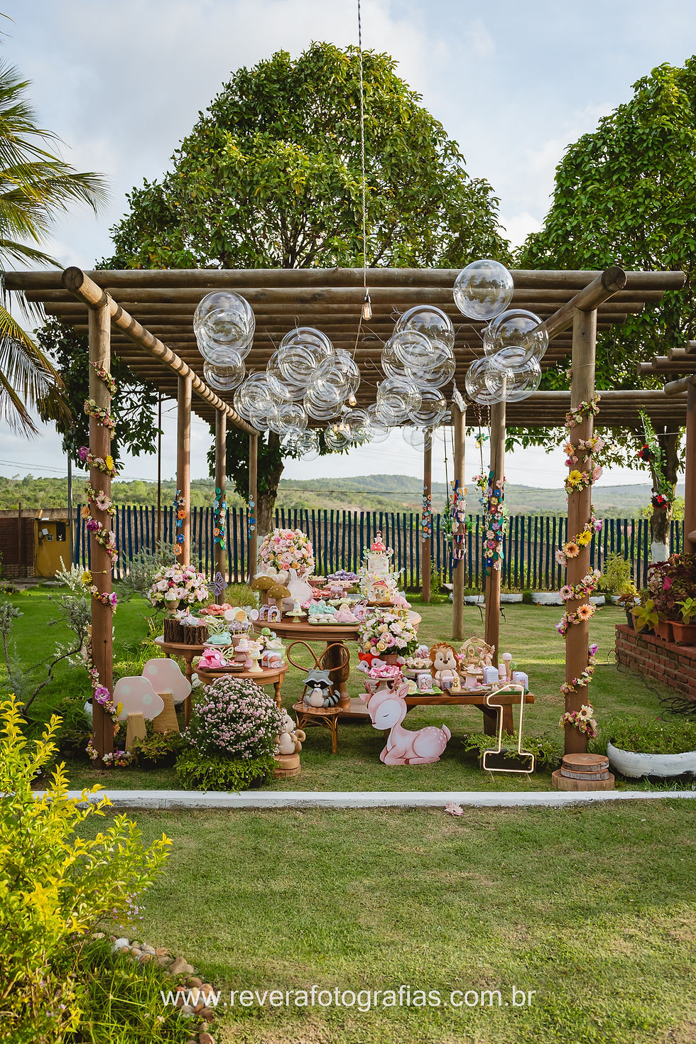 mãe e pai brincando com bebês na frente da decoração de festa infantil de 1 ano com tema borboletas