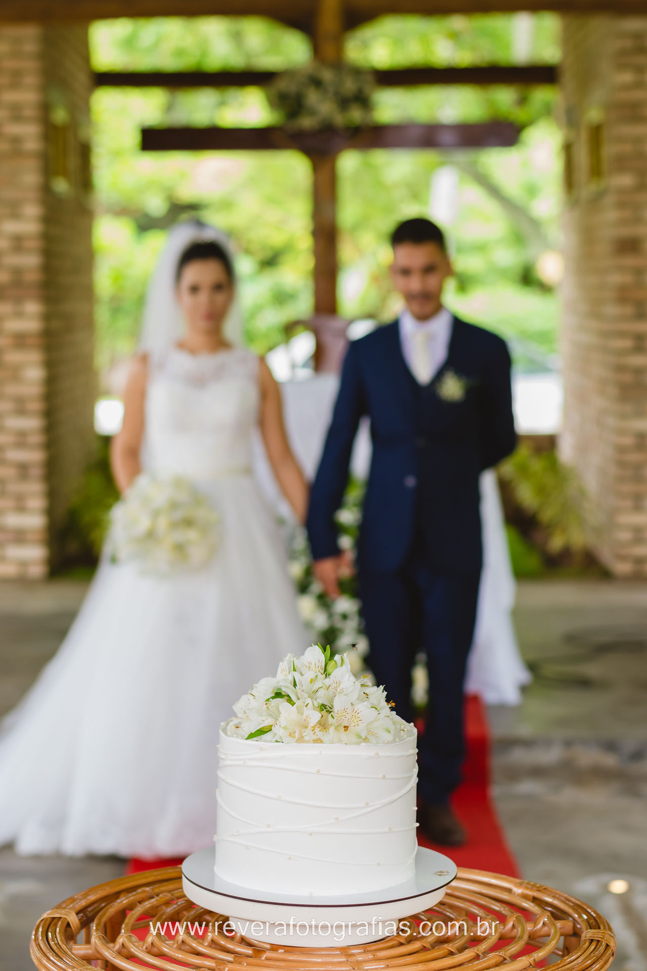 reverá fotografias: fotografia de fotógrafa profissional de cerimônia de casamento intimista de dia em lugar bonito ao ar livre noivo e noiva em frente ao bolo de casamento branco com flores na igreja capela nossa senhora desatadora dos nós em aracaju Nossa Senhora da Glória Tobias Barreto Lagarto Estância Simão Dias Penedo Itabaiana Itabaianinha São Cristóvão Estância Propriá Lagarto