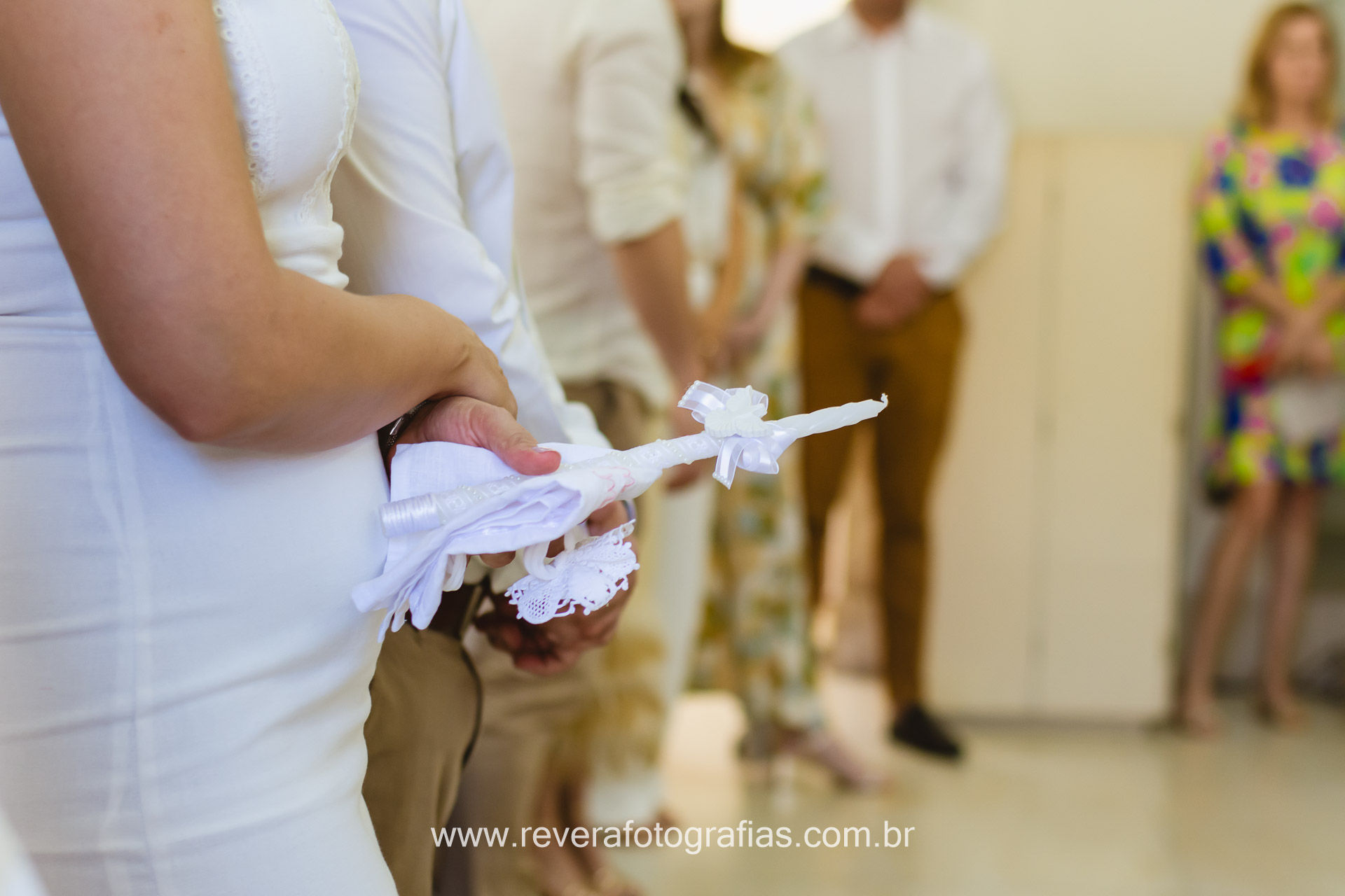 foto de detalhe de mãe segurando uma vela em cerimônia de batismo