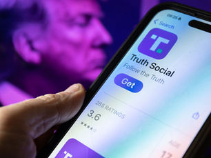 Donald Trump tenant un téléphone intelligent à proximité du logo de Truth Social.