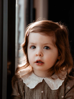 Girl in sage green dress next to window