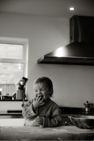 Black and white image of a child laughing at a kitchen counter top