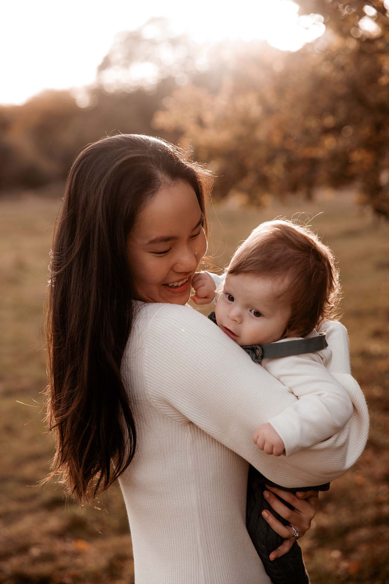 Mum holds small baby in glowing sunshine