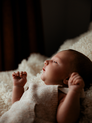 Newborn baby with hand up on soft blanket