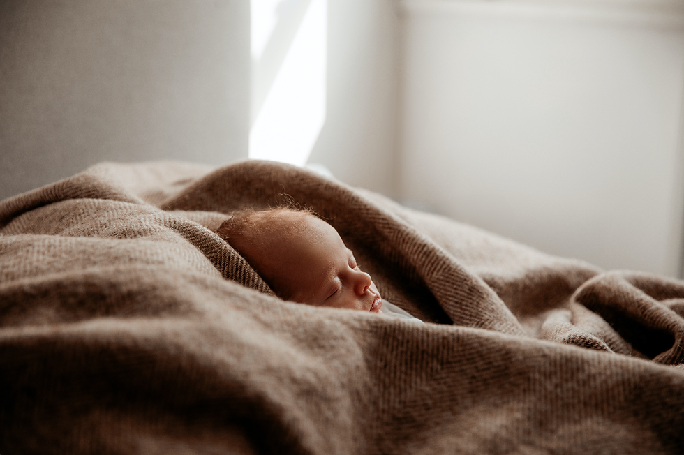 A newborn is asleep snuggled in blankets