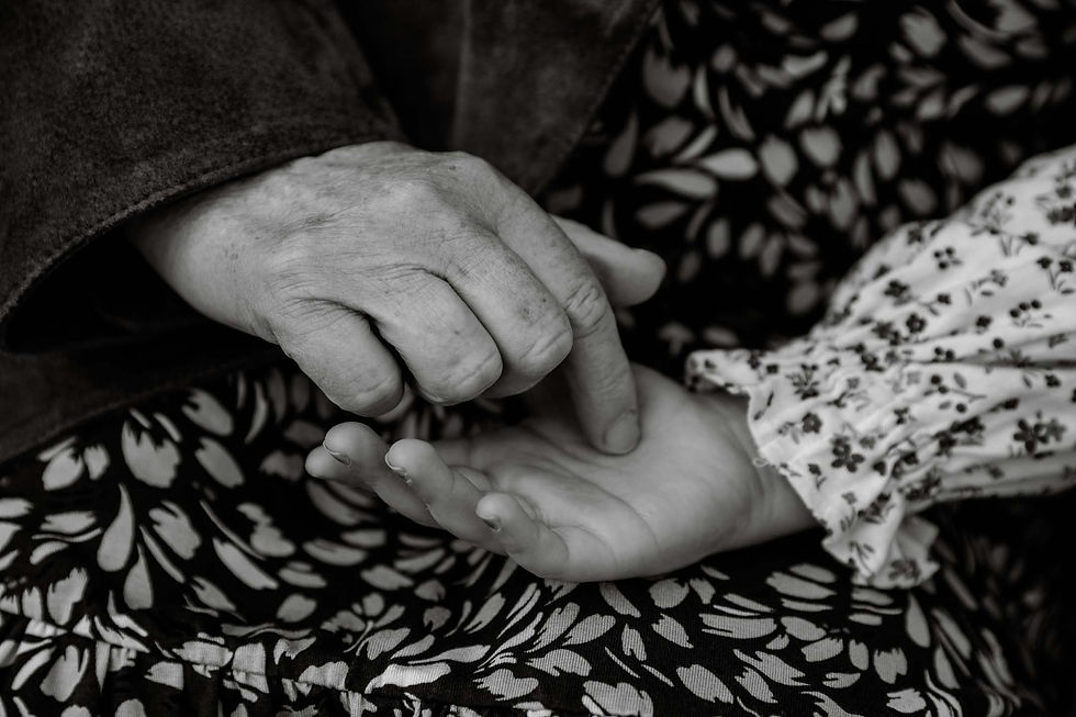 Black and white photograph of grandparent's hands holding young child's hands