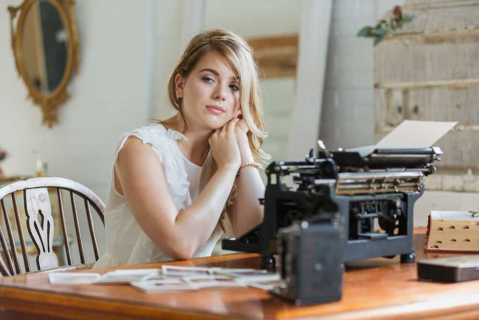 Woman sits at desk with vintage typewriter and photos