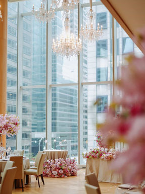 Elegant reception table setup with pink florals and a clear view of the Toronto skyline and CN Tower through floor-to-ceiling windows.
