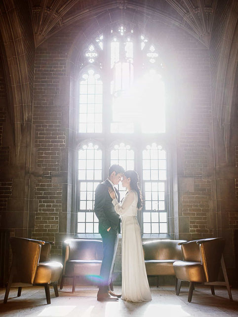 tmospheric silhouette engagement portrait in a moody historic Toronto interior with leaded glass windows.