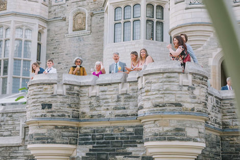 Wedding party cheering from the stone battlements and balcony of the historic Casa Loma castle.