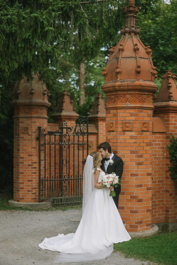  Romantic silhouette-style portrait of a couple embracing inside a grand historic stone gateway at Guild Park.