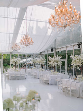 Elegant Toronto wedding reception decor featuring all-white floral arrangements and sophisticated table settings in a bright tent venue.
