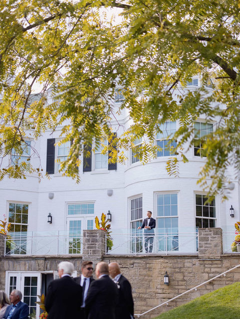 Unscripted candid moment of wedding guests gathered outside a grand luxury estate venue in Toronto.