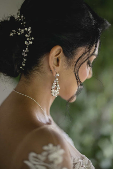 Close-up portrait of a bride wearing delicate jewelry and flowers, focusing on her elegant profile and soft expression.