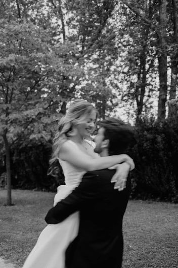 Expressive black and white candid of a groom lifting and swirling his bride during a romantic outdoor session.