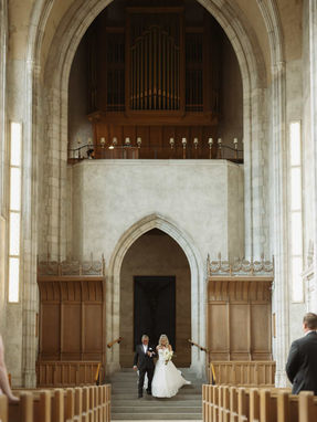  High-angle photography capturing a bride and groom walking down the aisle of Trinity College Chapel at U of T.